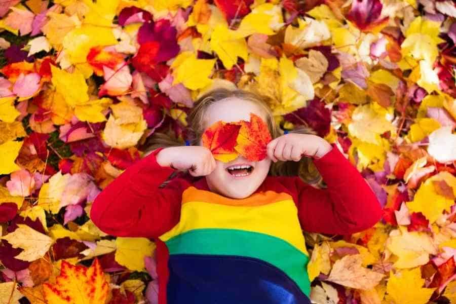 girl playing in fall leaves