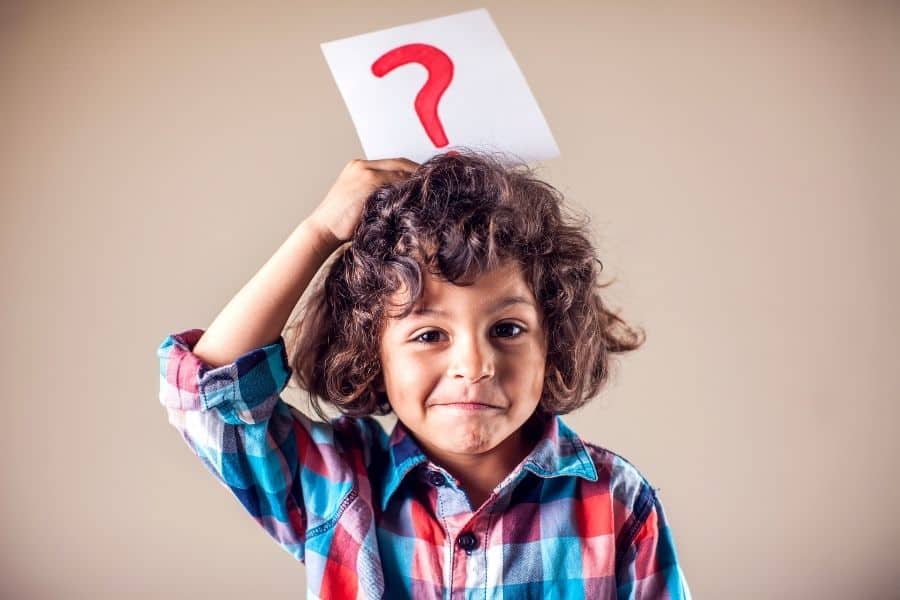 child holding a question mark sign over his head